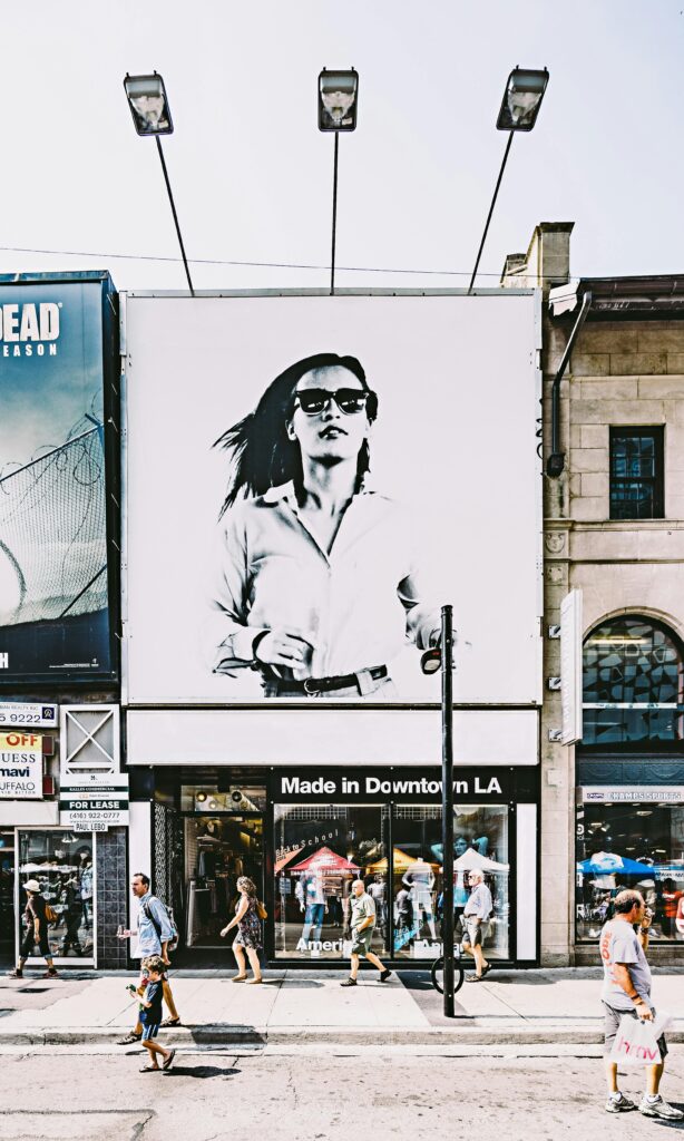 Busy Toronto street with shops, people, and large advertisement in urban setting.